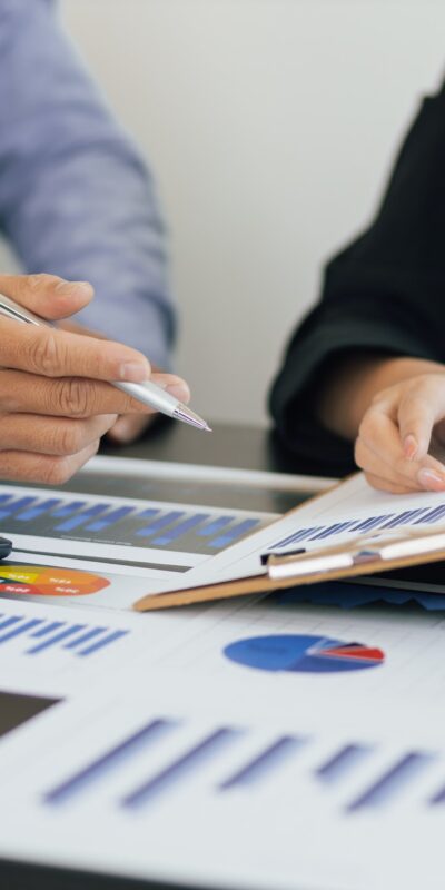 Two professionals discuss financial reports and data analysis, with a calculator and charts on the table.